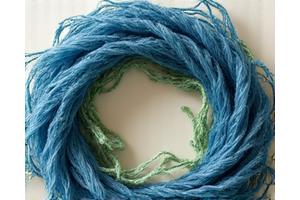 다양한 색상의 재활용 섬유가 원형으로 배열되어 순환 경제와 친환경성을 상징하는 모습. 자연 친화적인 톤의 색상.